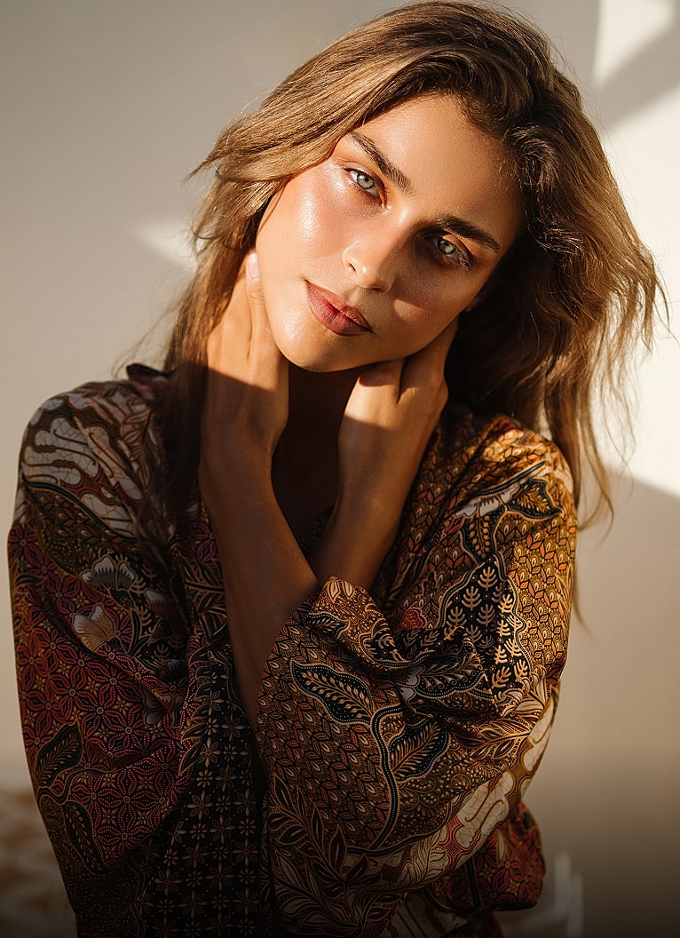 Woman in patterned clothing with soft natural light.