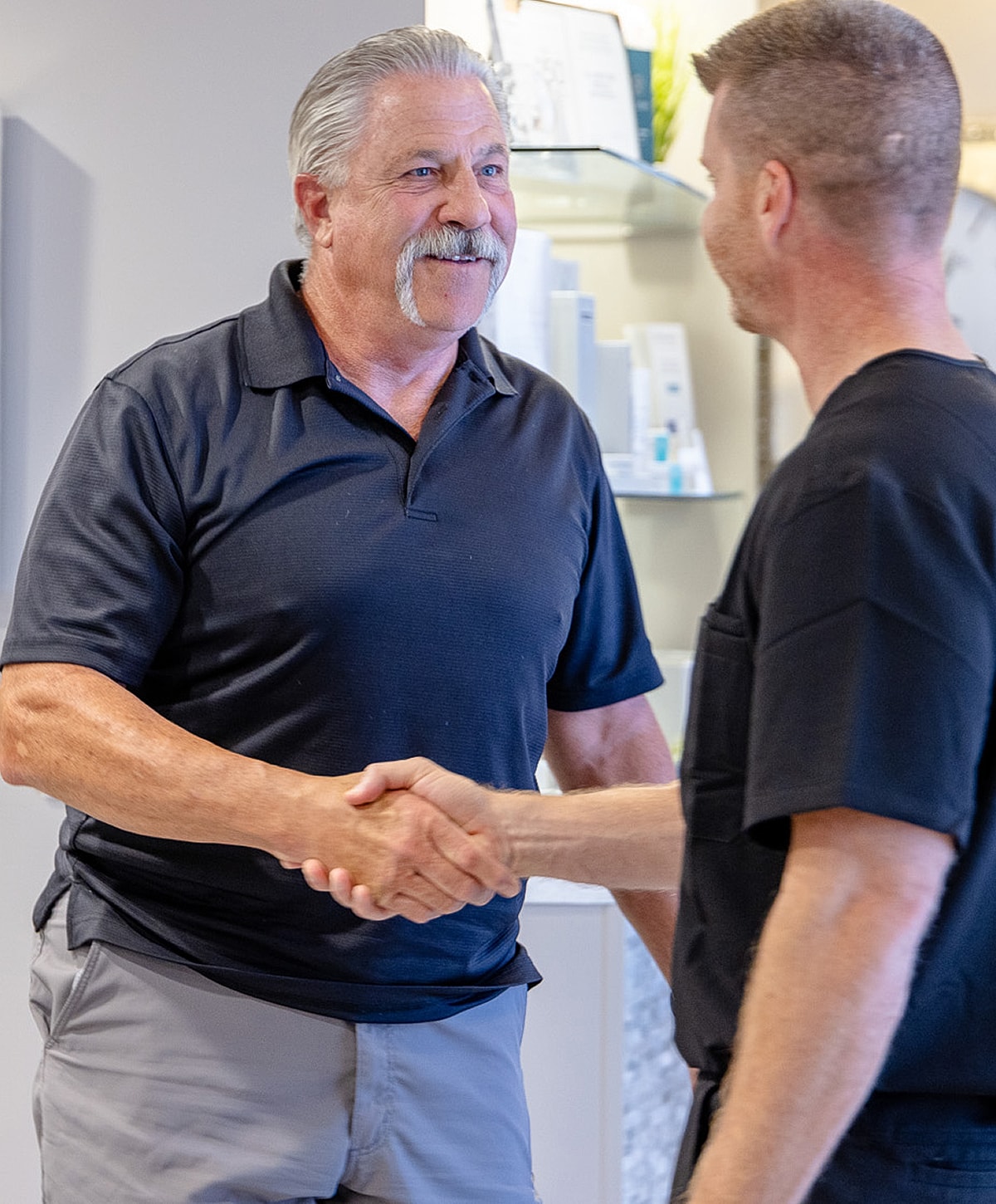 Two men shaking hands in a welcoming setting.