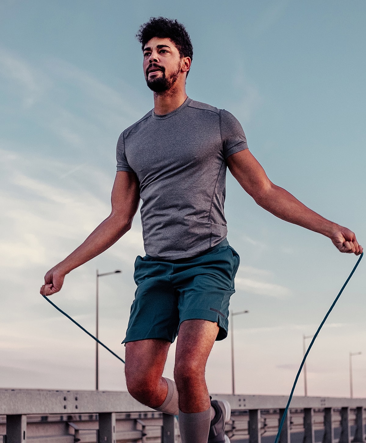 Man skipping rope outdoors at sunset.
