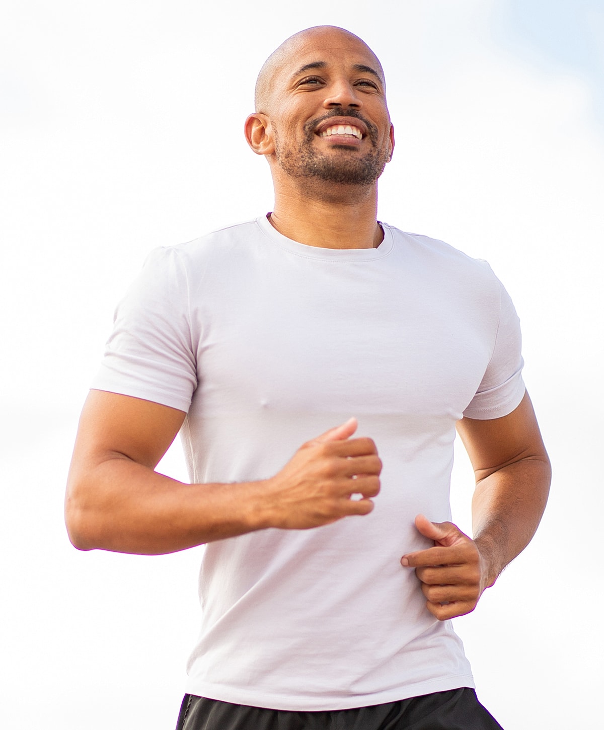 Smiling man jogging outdoors in athletic attire.