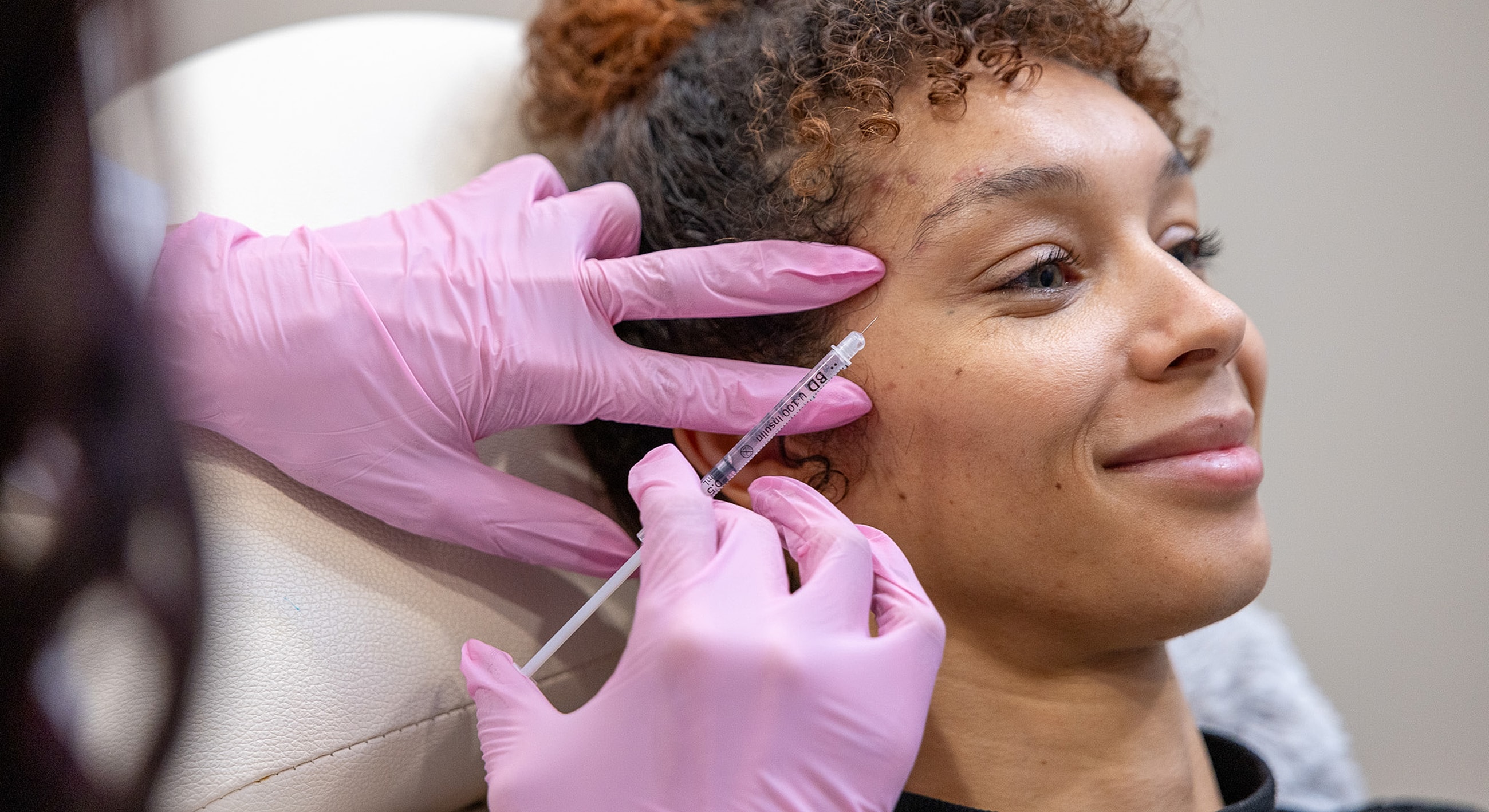 Patient receiving aesthetic treatment with syringe.