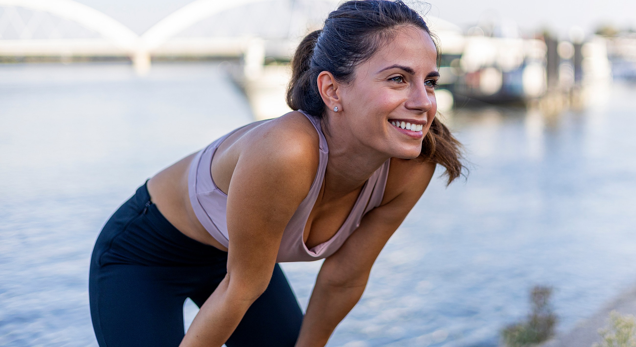 Smiling woman exercising by the water.